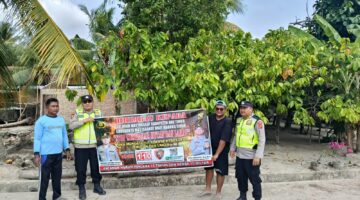 Personel Polsek Buay Madang Timur bersama warga membentangkan spanduk imbauan 