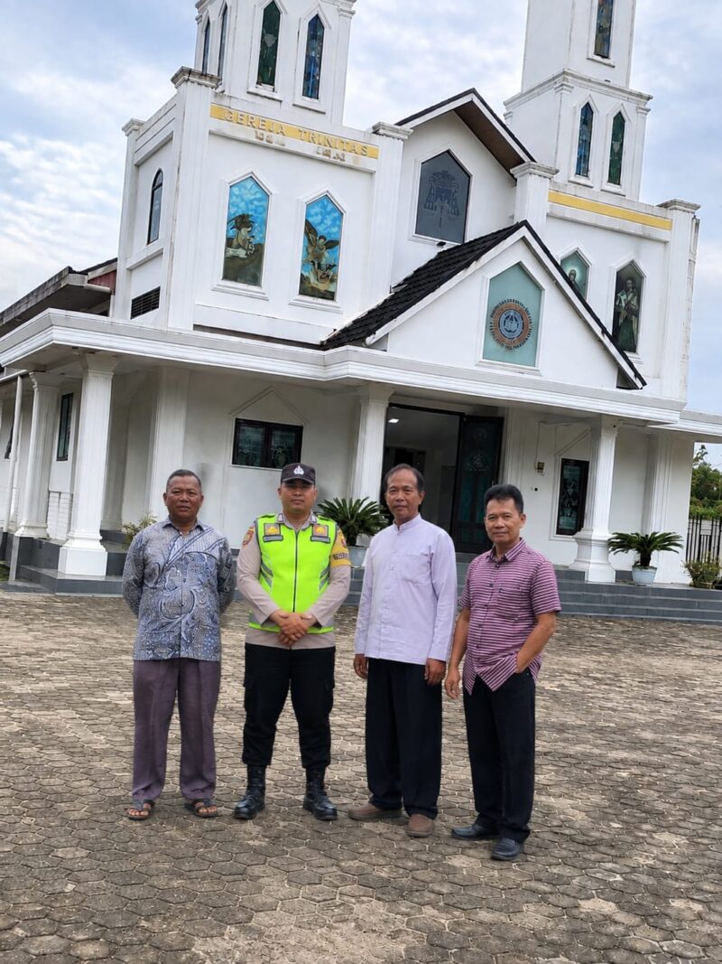 Personel Kepolisian Sektor (Polsek) Buay Madang Timur berfoto bersama Romo Susilo Haryono, dan pengurus Gereja Katolik Trinitas di Desa Bangun Sari (BK 3), Kecamatan Buay Madang Timur, Kabupaten OKU Timur. 