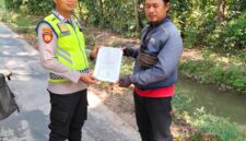 Personel Polsek Buay Madang Timur, Bripka Iswanto menyerahkan lembaran kertas Maklumat Karhutla kepada seorang warga saat menggelar kegiatan sambang di Desa Tanjung Sari, Kecamatan Buay Madang Timur, Kabupaten OKU Timur. 