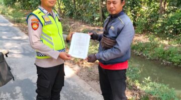 Personel Polsek Buay Madang Timur, Bripka Iswanto menyerahkan lembaran kertas Maklumat Karhutla kepada seorang warga saat menggelar kegiatan sambang di Desa Tanjung Sari, Kecamatan Buay Madang Timur, Kabupaten OKU Timur. 