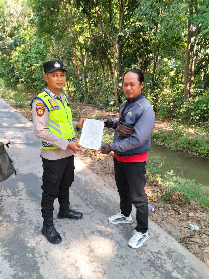 Personel Polsek Buay Madang Timur, Bripka Iswanto menyerahkan lembaran kertas Maklumat Karhutla kepada seorang warga saat menggelar kegiatan sambang di Desa Tanjung Sari, Kecamatan Buay Madang Timur, Kabupaten OKU Timur. 