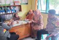 Anggota Bhabinkamtibmas Polsek Buay Madang Timur, Aipda Sahrul, berdialog dengan staf kesehatan dan warga di Puskesmas Pembantu Tanjung Mas, Desa Tanjung Mulya, Kecamatan Buay Madang Timur, Kabupaten OKU Timur. 