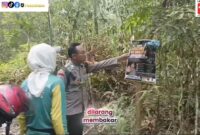 Personel Bhabinkamtibmas Polsek Buay Madang Timur, Brigadir Tedy Heryadi, memasang spanduk edukasi larangan membakar lahan di kawasan hutan Desa Kedung Rejo, OKU Timur.