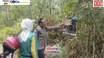 Personel Bhabinkamtibmas Polsek Buay Madang Timur, Brigadir Tedy Heryadi, memasang spanduk edukasi larangan membakar lahan di kawasan hutan Desa Kedung Rejo, OKU Timur.