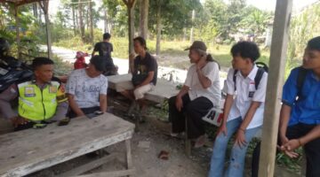 Personel Polsek Buay Madang Timur, Aipda Sahrul Munir, berdialog dan memberikan imbauan kamtibmas kepada warga serta pelajar di area Balai Desa Sumber Harjo, Kecamatan Buay Madang Timur, OKU Timur.