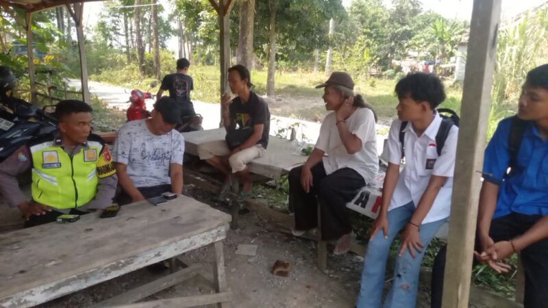 Personel Polsek Buay Madang Timur, Aipda Sahrul Munir, berdialog dan memberikan imbauan kamtibmas kepada warga serta pelajar di area Balai Desa Sumber Harjo, Kecamatan Buay Madang Timur, OKU Timur.
