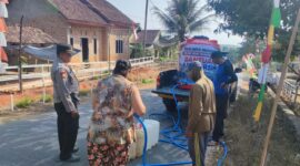 Kapolsek Buay Madang Timur Iptu Swisspo, memantau langsung pengisian air bersih ke jeriken milik seorang warga di Desa Teko Rejo, Kecamatan Buay Madang Timur, Kabupaten OKU Timur.