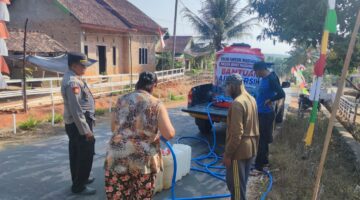 Kapolsek Buay Madang Timur Iptu Swisspo, memantau langsung pengisian air bersih ke jeriken milik seorang warga di Desa Teko Rejo, Kecamatan Buay Madang Timur, Kabupaten OKU Timur.