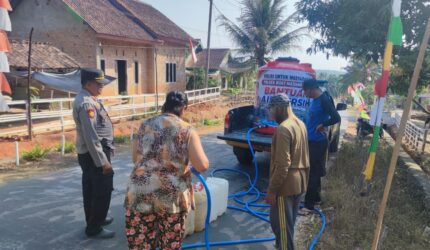 Kapolsek Buay Madang Timur Iptu Swisspo, memantau langsung pengisian air bersih ke jeriken milik seorang warga di Desa Teko Rejo, Kecamatan Buay Madang Timur, Kabupaten OKU Timur.