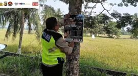 Kapolsek Buay Madang Timur Iptu Swisspo, memasang spanduk imbauan larangan membakar sampah dan daun kering di sebuah pohon di kawasan Desa Sumedang Sari, Kecamatan Buay Madang Timur, Kab. OKU Timur.