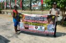 Personel piket Polsek Buay Madang Timur, Aipda Zulkifli dan Bripka Iswanto, membentangkan spanduk maklumat bersama warga saat melaksanakan Giat Sambang dan Sosialisasi Pencegahan Kebakaran Hutan dan Lahan (Karhutla) di wilayah Kecamatan Buay Madang Timur, Kabupaten OKU Timur.
