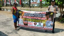 Personel piket Polsek Buay Madang Timur, Aipda Zulkifli dan Bripka Iswanto, membentangkan spanduk maklumat bersama warga saat melaksanakan Giat Sambang dan Sosialisasi Pencegahan Kebakaran Hutan dan Lahan (Karhutla) di wilayah Kecamatan Buay Madang Timur, Kabupaten OKU Timur.