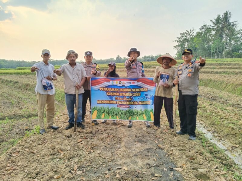 Kapolsek Buay Madang Timur Iptu Swisspo, bersama jajaran personel Polsek BMT, perangkat desa, dan petani setempat membentangkan spanduk saat aksi penanaman jagung serentak Kuartal III Tahun 2026 di Desa Gumuk Rejo, Kecamatan Buay Madang Timur, Kabupaten OKU Timur, Sumatera Selatan.
