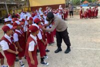 Kapolsek Buay Madang Timur Iptu Swisspo, memasangkan masker secara langsung kepada seorang siswa saat memimpin kegiatan Goes To School di SDN 2 Teko Rejo, Kabupaten OKU Timur.