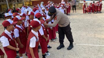 Kapolsek Buay Madang Timur Iptu Swisspo, memasangkan masker secara langsung kepada seorang siswa saat memimpin kegiatan Goes To School di SDN 2 Teko Rejo, Kabupaten OKU Timur.