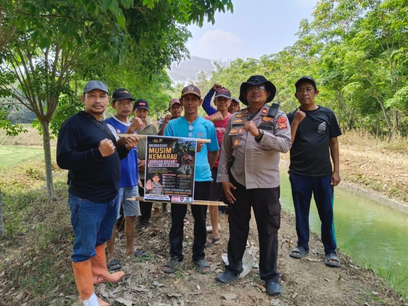 Kapolsek Buay Madang Timur Iptu Swisspo, bersama perangkat desa dan warga membentangkan pamflet imbauan larangan membakar lahan saat menggelar patroli mitigasi Karhutla di Desa Tambak Boyo, Kecamatan Buay Madang Timur, Kabupaten OKU Timur.