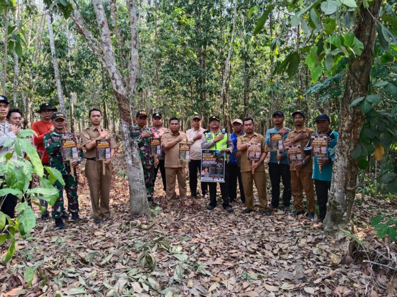 Kapolsek Buay Madang Timur (BMT) Iptu Swisspo, bersama Camat BMT Ramadhan Agusten, personel Koramil 403-05 Buay Madang, perangkat desa, serta Masyarakat Peduli Api berfoto bersama sambil membentangkan selebaran imbauan saat patroli gabungan mitigasi Karhutla di Desa Gumuk Rejo, OKU Timur.