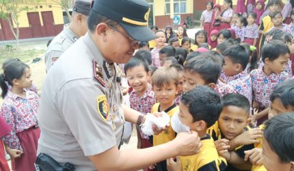 Kapolsek Buay Madang Timur (BMT) Iptu Swisspo, memasangkan masker secara langsung kepada salah seorang murid saat menggelar program Cooling System / Goes To School di SDN Rejodadi, Desa Rejodadi, Kecamatan Buay Madang Timur, OKU Timur.