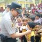 Kapolsek Buay Madang Timur (BMT) Iptu Swisspo, memasangkan masker secara langsung kepada salah seorang murid saat menggelar program Cooling System / Goes To School di SDN Rejodadi, Desa Rejodadi, Kecamatan Buay Madang Timur, OKU Timur.