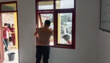 Personil Polsek Buay Madang Timur (BMT) membersihkan kaca dan area jendela saat melaksanakan program Belida (Bersih Lingkungan dan Asri) di Rumah Dinas Polsek BMT, Kabupaten OKU Timur.