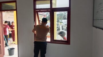 Personil Polsek Buay Madang Timur (BMT) membersihkan kaca dan area jendela saat melaksanakan program Belida (Bersih Lingkungan dan Asri) di Rumah Dinas Polsek BMT, Kabupaten OKU Timur.