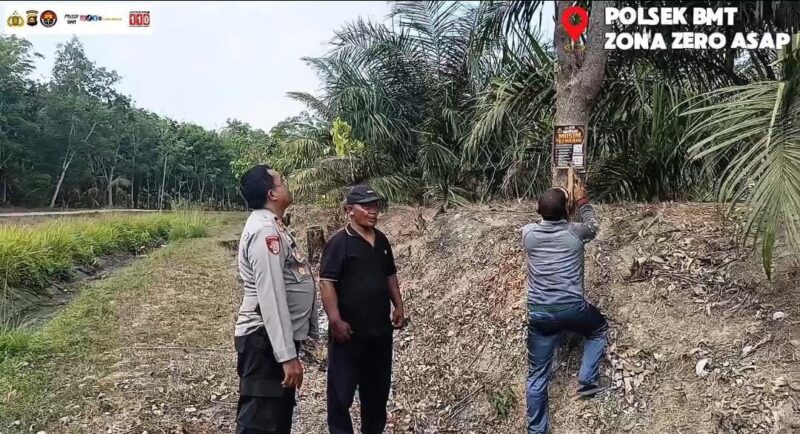Kapolsek Buay Madang Timur (BMT) Iptu Swisspo, memantau pemasangan spanduk imbauan larangan membakar lahan di kawasan perkebunan Desa Tambak Boyo, OKU Timur, Sumatera Selatan.