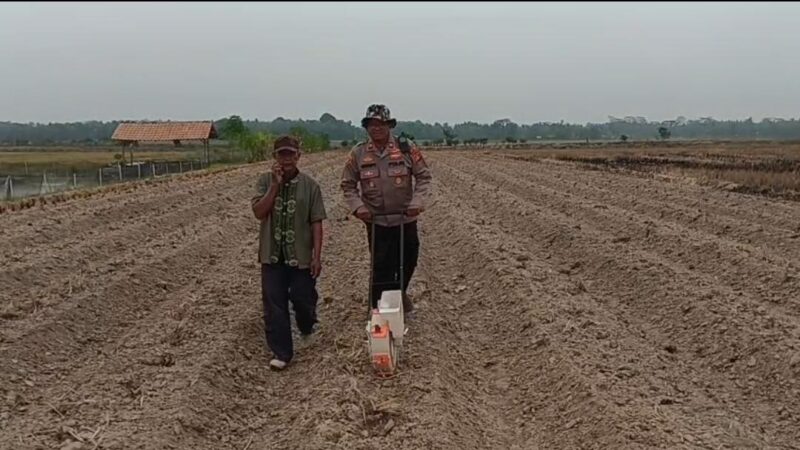 Kapolsek Buay Madang Timur Iptu Swisspo, menggunakan alat penanam manual didampingi pemilik lahan, Wakidin, saat menanam jagung hibrida di Desa Tanjung Mas.
