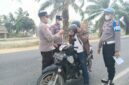 Kapolsek Buay Madang Timur, Iptu Swisspo, memakaikan masker gratis kepada seorang pengendara sepeda motor yang melintas di jalan raya Desa Karang Tengah, Kecamatan Buay Madang Timur, Kabupaten OKU Timur.