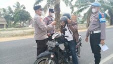Kapolsek Buay Madang Timur, Iptu Swisspo, memakaikan masker gratis kepada seorang pengendara sepeda motor yang melintas di jalan raya Desa Karang Tengah, Kecamatan Buay Madang Timur, Kabupaten OKU Timur.