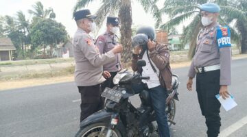 Kapolsek Buay Madang Timur, Iptu Swisspo, memakaikan masker gratis kepada seorang pengendara sepeda motor yang melintas di jalan raya Desa Karang Tengah, Kecamatan Buay Madang Timur, Kabupaten OKU Timur.