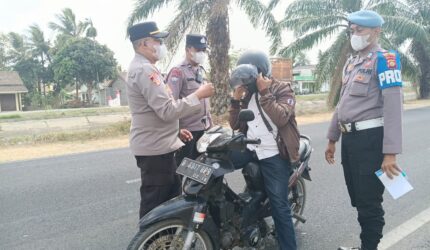 Kapolsek Buay Madang Timur, Iptu Swisspo, memakaikan masker gratis kepada seorang pengendara sepeda motor yang melintas di jalan raya Desa Karang Tengah, Kecamatan Buay Madang Timur, Kabupaten OKU Timur.