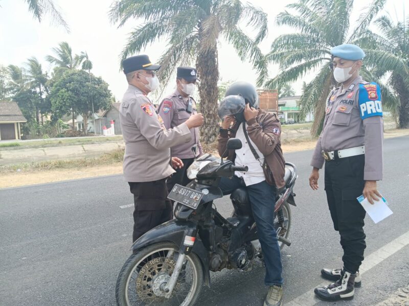 Kapolsek Buay Madang Timur, Iptu Swisspo, memakaikan masker gratis kepada seorang pengendara sepeda motor yang melintas di jalan raya Desa Karang Tengah, Kecamatan Buay Madang Timur, Kabupaten OKU Timur.