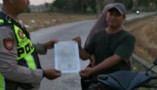 Personel Polsek Buay Madang Timur, Aipda Khoirul, menyerahkan lembaran Maklumat Kapolda Sumsel terkait larangan pembakaran hutan dan lahan kepada pengendara motor di Desa Sumber Mulyo, OKU Timur.
