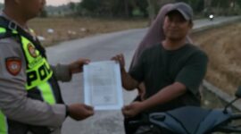Personel Polsek Buay Madang Timur, Aipda Khoirul, menyerahkan lembaran Maklumat Kapolda Sumsel terkait larangan pembakaran hutan dan lahan kepada pengendara motor di Desa Sumber Mulyo, OKU Timur.