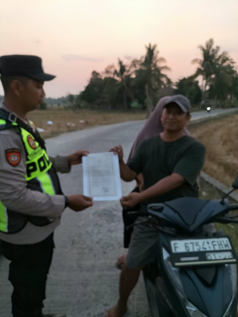 Personel Polsek Buay Madang Timur, Aipda Khoirul, menyerahkan lembaran Maklumat Kapolda Sumsel terkait larangan pembakaran hutan dan lahan kepada pengendara motor di Desa Sumber Mulyo, OKU Timur.