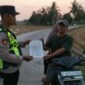 Personel Polsek Buay Madang Timur, Aipda Khoirul, menyerahkan lembaran Maklumat Kapolda Sumsel terkait larangan pembakaran hutan dan lahan kepada pengendara motor di Desa Sumber Mulyo, OKU Timur.