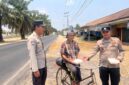 Bhabinkamtibmas Polsek Buay Madang Timur Aipda Wisnu Saputra didampingi Kanit Binmas Bripka Ari Wicaksono membagikan paket makanan kepada seorang warga pesepeda di Desa Karang Tengah, Kecamatan Buay Madang Timur, Kabupaten OKU Timur.