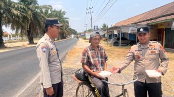 Bhabinkamtibmas Polsek Buay Madang Timur Aipda Wisnu Saputra didampingi Kanit Binmas Bripka Ari Wicaksono membagikan paket makanan kepada seorang warga pesepeda di Desa Karang Tengah, Kecamatan Buay Madang Timur, Kabupaten OKU Timur.