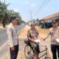 Bhabinkamtibmas Polsek Buay Madang Timur Aipda Wisnu Saputra didampingi Kanit Binmas Bripka Ari Wicaksono membagikan paket makanan kepada seorang warga pesepeda di Desa Karang Tengah, Kecamatan Buay Madang Timur, Kabupaten OKU Timur.
