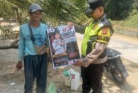 Personel Polsek Buay Madang Timur menunjukkan poster maklumat larangan membakar hutan dan lahan bersama seorang warga saat menggelar kegiatan mitigasi di wilayah Kecamatan Buay Madang Timur, Kabupaten OKU Timur.