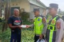 Ka SPKT Polsek Buay Madang Timur Aipda Khoirul Alkaf menyerahkan paket makanan siap saji kepada seorang warga dalam kegiatan sedekah dan berbagi di seputaran wilayah Desa Karang Tengah, Kecamatan Buay Madang Timur, Kabupaten OKU Timur.