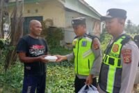 Ka SPKT Polsek Buay Madang Timur Aipda Khoirul Alkaf menyerahkan paket makanan siap saji kepada seorang warga dalam kegiatan sedekah dan berbagi di seputaran wilayah Desa Karang Tengah, Kecamatan Buay Madang Timur, Kabupaten OKU Timur.