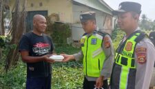 Ka SPKT Polsek Buay Madang Timur Aipda Khoirul Alkaf menyerahkan paket makanan siap saji kepada seorang warga dalam kegiatan sedekah dan berbagi di seputaran wilayah Desa Karang Tengah, Kecamatan Buay Madang Timur, Kabupaten OKU Timur.