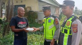 Ka SPKT Polsek Buay Madang Timur Aipda Khoirul Alkaf menyerahkan paket makanan siap saji kepada seorang warga dalam kegiatan sedekah dan berbagi di seputaran wilayah Desa Karang Tengah, Kecamatan Buay Madang Timur, Kabupaten OKU Timur.