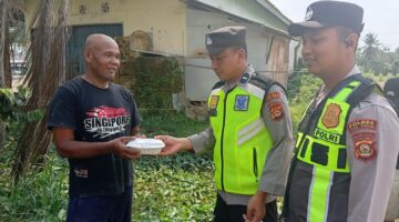 Ka SPKT Polsek Buay Madang Timur Aipda Khoirul Alkaf menyerahkan paket makanan siap saji kepada seorang warga dalam kegiatan sedekah dan berbagi di seputaran wilayah Desa Karang Tengah, Kecamatan Buay Madang Timur, Kabupaten OKU Timur.