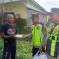 Ka SPKT Polsek Buay Madang Timur Aipda Khoirul Alkaf menyerahkan paket makanan siap saji kepada seorang warga dalam kegiatan sedekah dan berbagi di seputaran wilayah Desa Karang Tengah, Kecamatan Buay Madang Timur, Kabupaten OKU Timur.