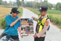 Personel Polsek Buay Madang Timur menunjukkan poster Maklumat Kapolda Sumsel tentang larangan membakar hutan dan lahan kepada seorang pengendara motor di kawasan Desa Tanjung Mulya, Kecamatan Buay Madang Timur, Kabupaten OKU Timur.