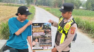 Personel Polsek Buay Madang Timur menunjukkan poster Maklumat Kapolda Sumsel tentang larangan membakar hutan dan lahan kepada seorang pengendara motor di kawasan Desa Tanjung Mulya, Kecamatan Buay Madang Timur, Kabupaten OKU Timur.