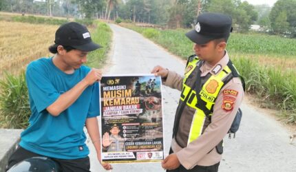 Personel Polsek Buay Madang Timur menunjukkan poster Maklumat Kapolda Sumsel tentang larangan membakar hutan dan lahan kepada seorang pengendara motor di kawasan Desa Tanjung Mulya, Kecamatan Buay Madang Timur, Kabupaten OKU Timur.