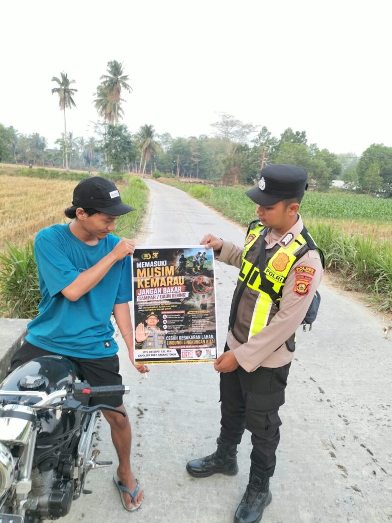 Personel Polsek Buay Madang Timur menunjukkan poster Maklumat Kapolda Sumsel tentang larangan membakar hutan dan lahan kepada seorang pengendara motor di kawasan Desa Tanjung Mulya, Kecamatan Buay Madang Timur, Kabupaten OKU Timur.